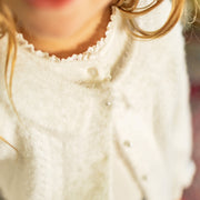 Zoom d'un enfant portant le cardigan blanc pelucheux, enfant