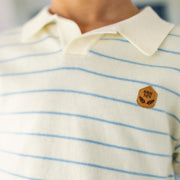 Zoom de l'écusson SRS MN au devant du polo crème et bleu en tricot à rayures, enfant
