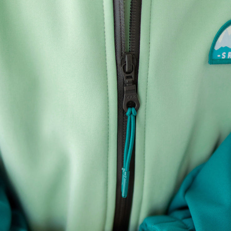Zoom du zipper du manteau à capuchon vert, turquoise et gris en coquille souple, enfant