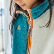 Détail de la veste en peluche bleue avec blocs de couleur, enfant