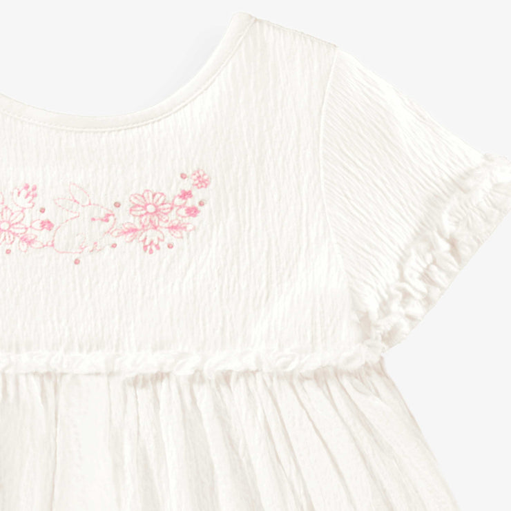 Détail de la robe blanche en jersey crêpé avec broderies de fleurs, bébé